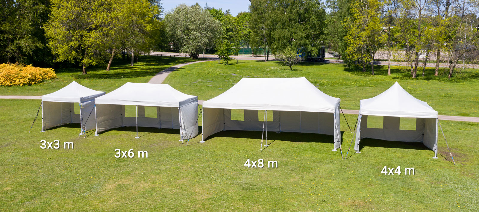Neljä erikokoista harmaata pop up telttaa nurmikolla