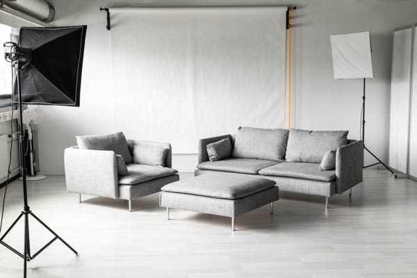 Nordic-sarjan harmaa sohva, nojatuoli ja rahi valokuvausstudiossa