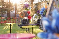 Isoin tekokukin somistettuja Tokyo riipputuoleja sekä värikansin varustettuja pyöreitä Basso kahvipöytiämme ulkona kesäillassa