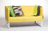 Keltainen vuokrasohva Pixel ja somistetyynyjä ja somistehuopia