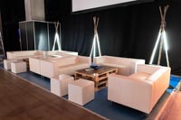 Valkoisen ja puun yhdistelmää messuilla (kuva rakennusvaiheesta) Valkoisia sohvia, raheja ja kuormalasohvapöytä