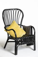 Esimerkki tyynystä ja viltistä Garden-nojatuolissa Keltainen somistetyyny ja harmaa viltti rottinkinojatuolissa