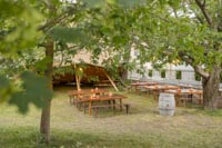 Rustiikkisia penkkipöytäsettejä puutarhamaisessa miljöössä laavun edessä Tuska Festivaaleilla Rustiikkisia penkkipöytäsettejä puutarhamaisessa miljöössä laavun edessä