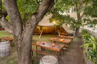 Rustiikkisia penkkipöytäsettejä puutarhamaisessa miljöössä sekä tekoviherkasveja somisteina Rustiikkisia penkkipöytäsettejä puutarhamaisessa miljöössä sekä tekoviherkasveja somisteina