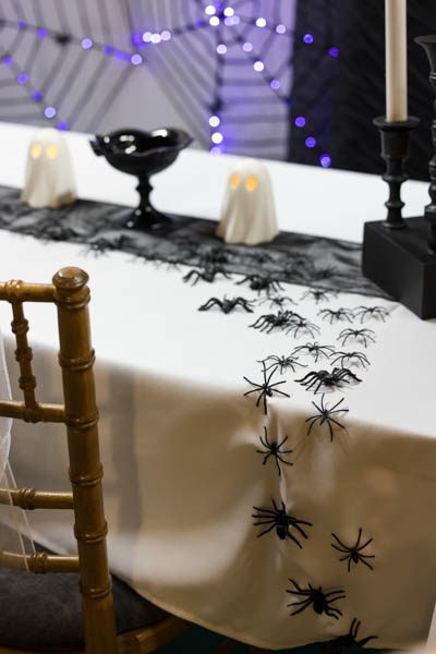 Halloween-pöytäsomistus missä muoviset hämähäkit kiipeävät sankoin joukoin pöydälle