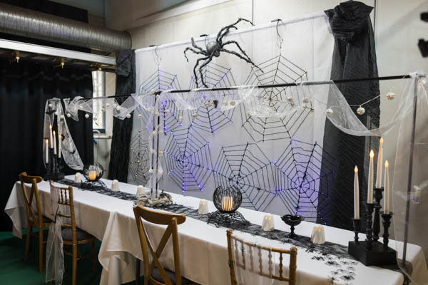 Pitkä suorakaidepöytä somistettuna mustavalkoisella teemalla Halloween-juhliin sopivaksi esimerkkikokonaisuudeksi.