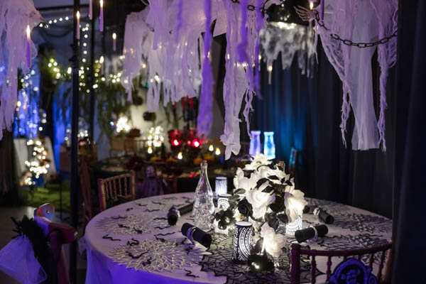 Mustavalkoinen pyöreän ruokapöydän somistus Halloween-teemalla. Katosta roikkuu valkoisia kummituksia ja tuoleina puiste Camelot- ja Greta-puutuolimme.