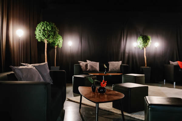 Lounge-tyyppinen tummaksi sisustettu oleskelutila yritystapahtumassa