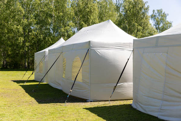 Eri kokoisia harmaita telttoja takapuolelta kuvattuna - osassa telttoja on ikkunaseinä