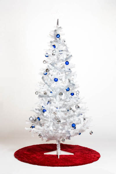 Valkoinen muovinen joulukuusi sinisillä ja hopeisilla koristeilla punaisen maton päällä