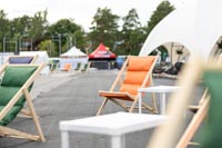 Oranssi aurinkotuoli ja vihreitä Beach kansituoleja festareilla