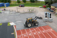 DuraDeck-lattiapaloja asetettu suojaamaan urheilukentän juoksurataa traktorin siirtäessä tavaraa tapahtuman rakennusvaiheessa