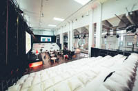 Kaksiosainen valkoinen katsomo istuintyynyillä Kattilahallissa Kaksiosainen valkoinen tilapäiskatsomo