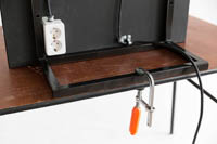 Meikkauspeilin takapuolella oleva metallijalka joka on kiinnitetty pöytään ruuvipuristimella. Kuvassa näkyy myös meikkauspeilin takaosan pistorasiat.