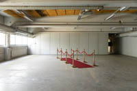 Punainen matto ja kahdeksan messingin väristä kulunohjainta punaisella köydellä pystytettynä varastomme yläkertaan