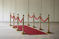 Punainen matto ja messinkisiä kulunohjaimia punaisella plyysiköydellä