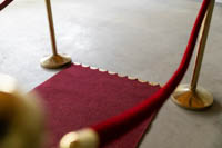 Punaisen maton pää messinkisillä heloilla ja messinkisiä Gala kulunohjaustolppia punaisella plyysiköydellä