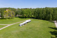 Neljä erikokoista harmaata telttaa nurmikkokentällä ilmakuvassa